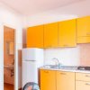 Cucinino arancione con frigorifero e piano cottura.