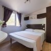 Camera da letto con letto matrimoniale, armadio scuro e finestra con tendaggi viola.