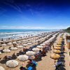 Ombrelloni ordinati su una spiaggia soleggiata.