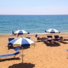 Spiaggia affollata con sdraio e ombrelloni blu.