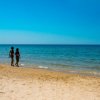 Due persone camminano su una spiaggia sabbiosa.