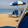 Spiaggia con lettini blu e ombrellone a righe.