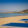 Spiaggia deserta con lettini blu e mare calmo.